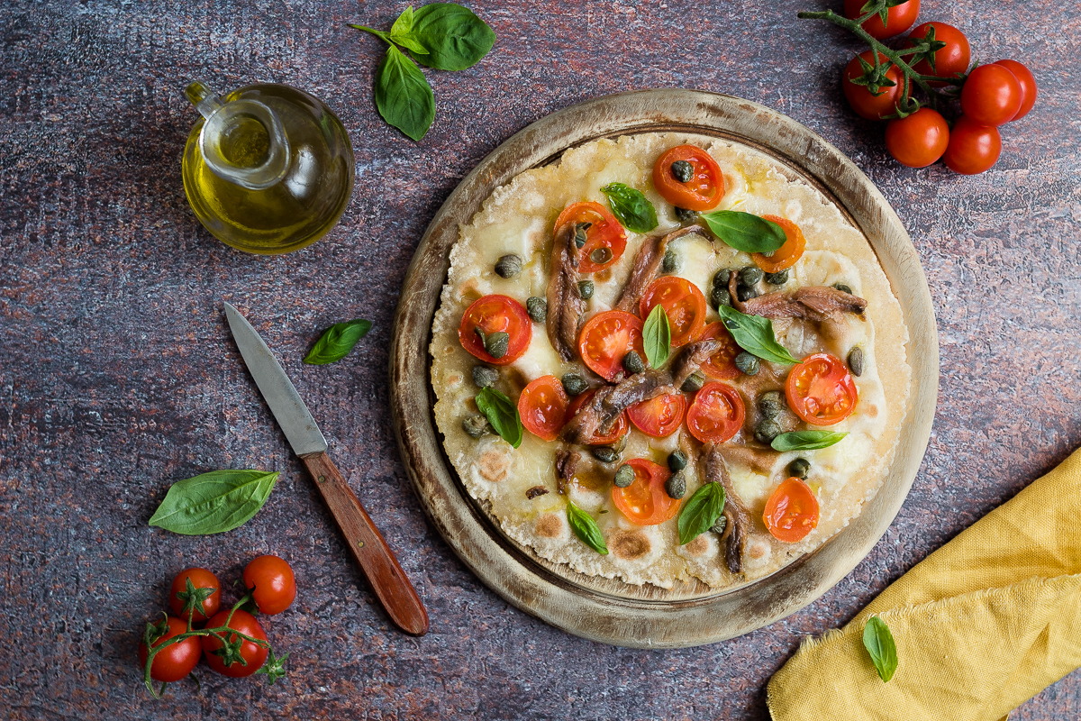 piadipizza con pomodorini mozzarella olive capperi e acciughe